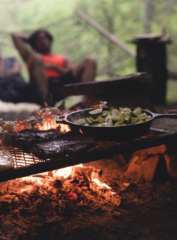 selective focus photo of skillet and meat on top of grill with fire