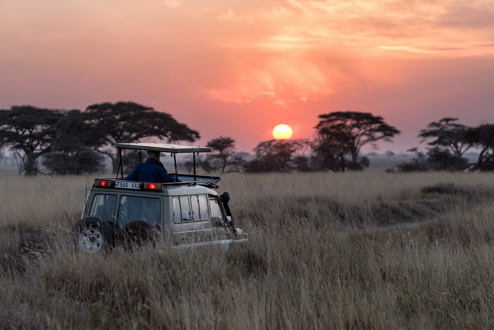 man riding on gray car during sunset in Africa